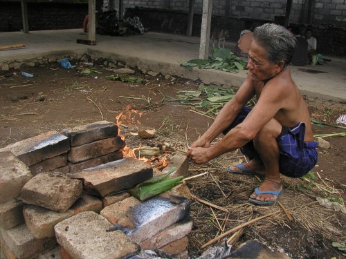 Ein Mann grillt Schweinefleischspießchen über dem offenen Feuer