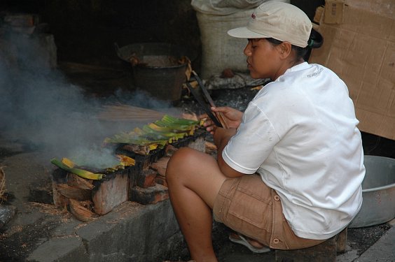 Eine Balinesin bereitet Ikan Pepes (Fisch in Bananenblatt) zu