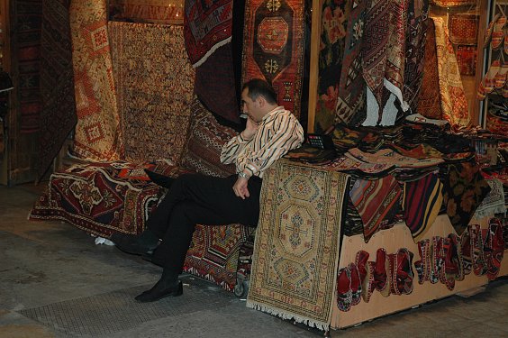 Teppiche (geknüpft) und Kelims (TürkCe kelimler und gewebt). Der Händler wirkt etwas gelangweilt. 
